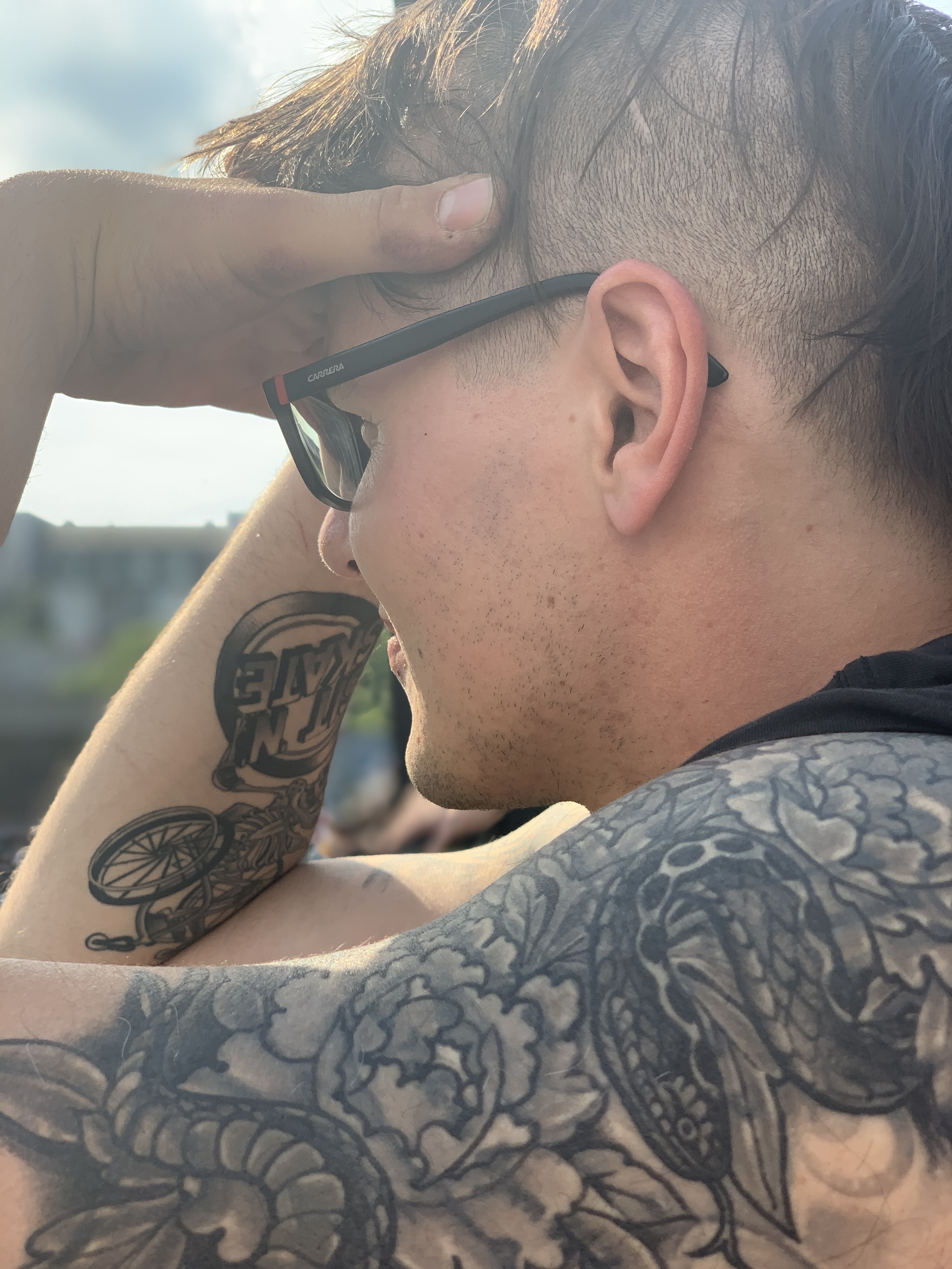 ein tattowierter weißer Mann stützt seinen Kopf an der Stirn ab und schaut nachdenklich in die Ferne