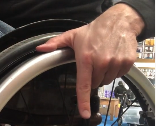 Der richtige Griff: Der Daumen liegt oben auf dem Greifreifen des Rollstuhls an, der abgespreizte Zeigefinger zeigt nach unten. Die restlichen Finger sind eingeklappt