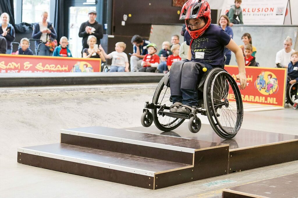 Foto eines Jungen mit Rollstuhl auf einem Treppenelement