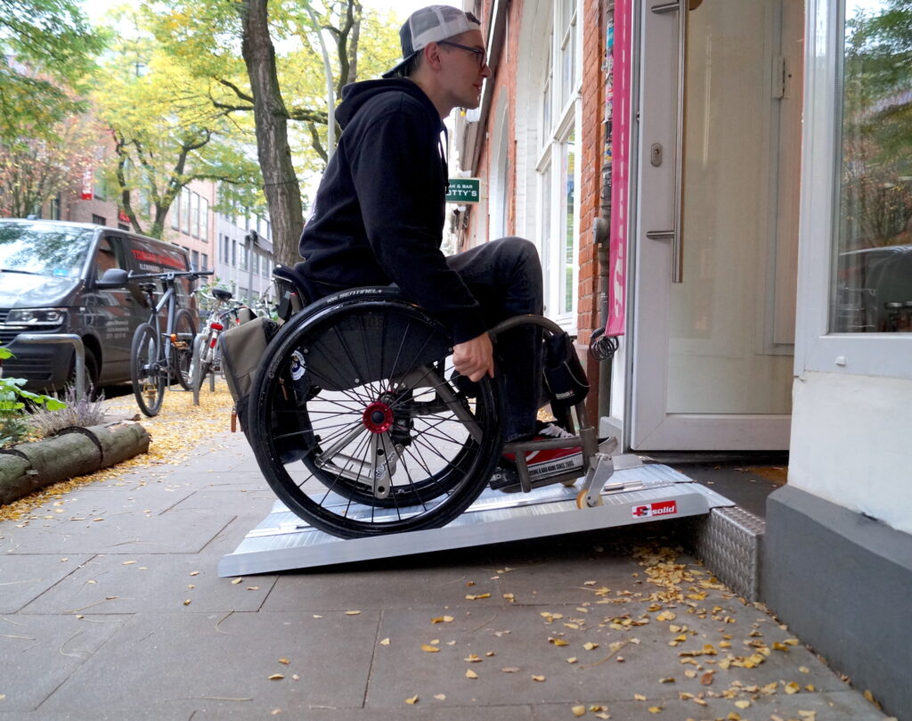 Ein Rollstuhlfahrer fährt auf einer Rampe in ein Geschäft.