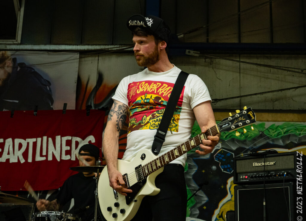 Ein Gitarrist auf der Bühne, im Hintergrund der Schlagzeuger.