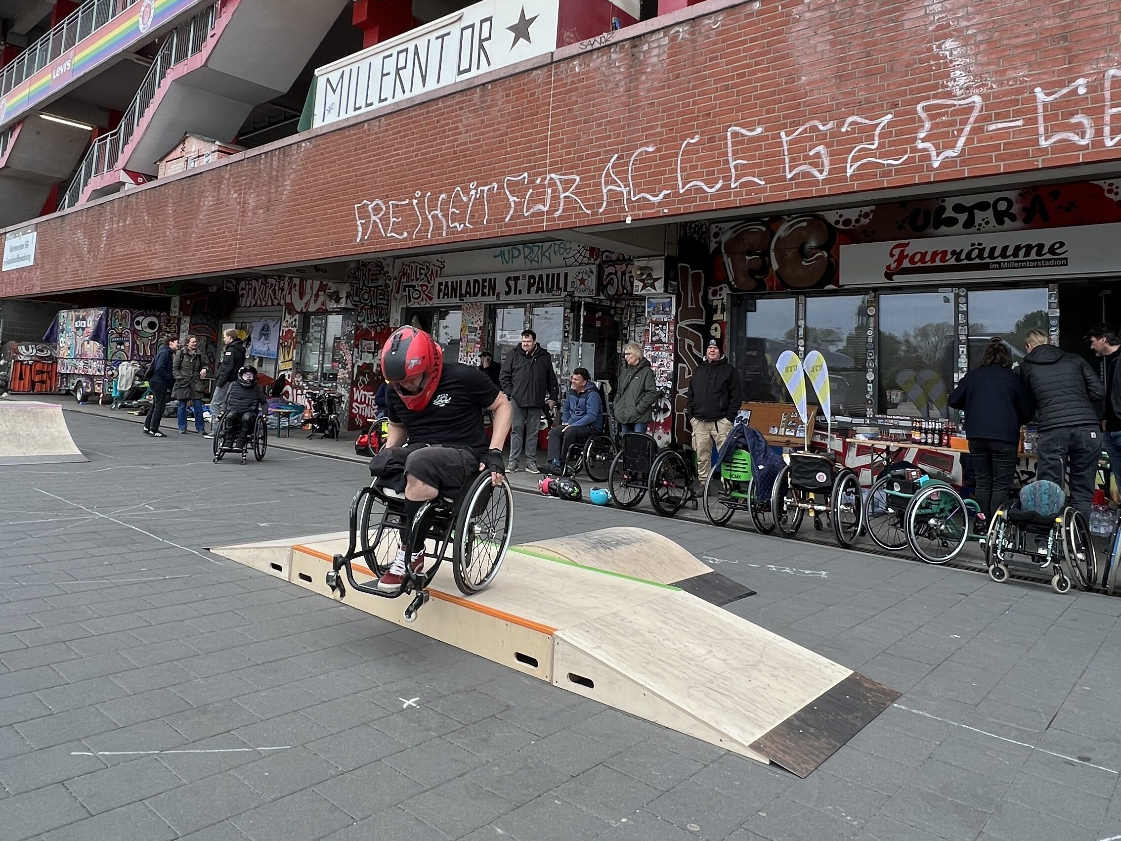 Ein Rollstuhlfahrer fährt über mobile Skaterampen vor dem Millerntorstadion.