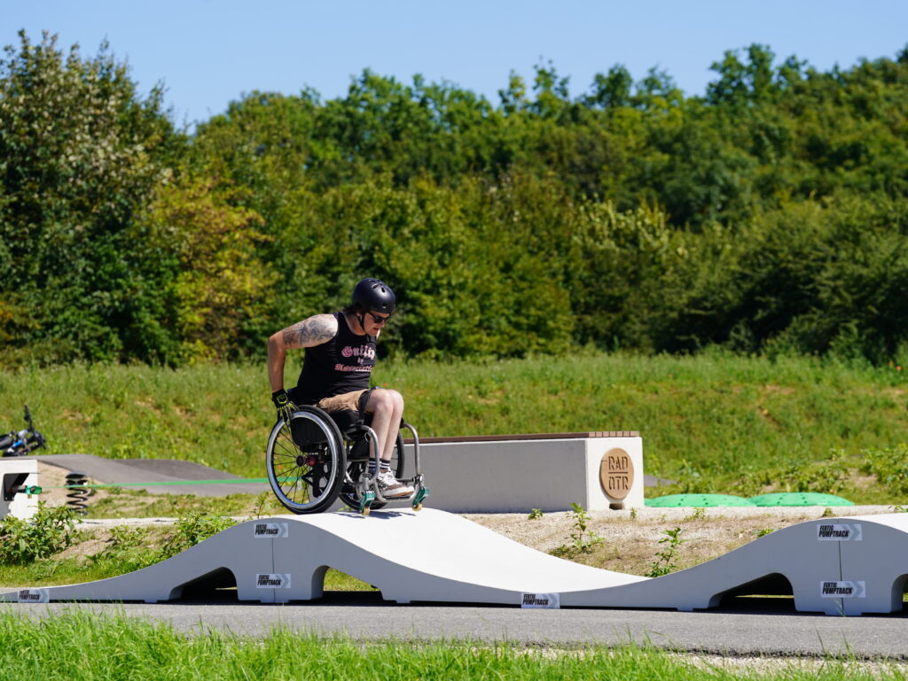 Ein Rollstuhlfahrer auf einem Pumptrack aus Kunststoff.