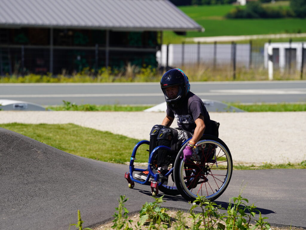 Ein Rollstuhlfahrer mit Fullface Helm auf einem Pumptrack.