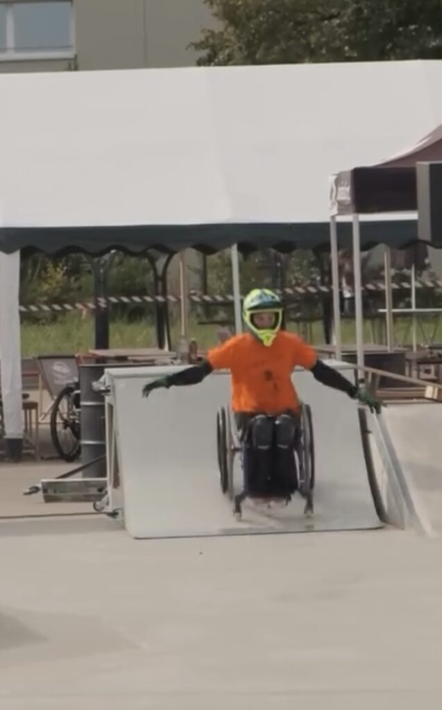 Eine Person im Rollsthl fährt eine Rampe runter. 