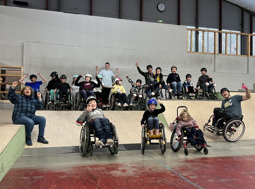 Gruppenbild von Menschen im Rollstuhl in einer Skatehalle.