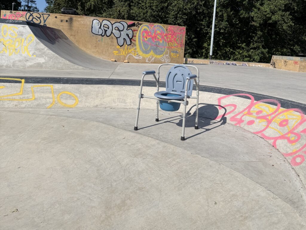 Eine Campingtoilette steht im Skatepark.