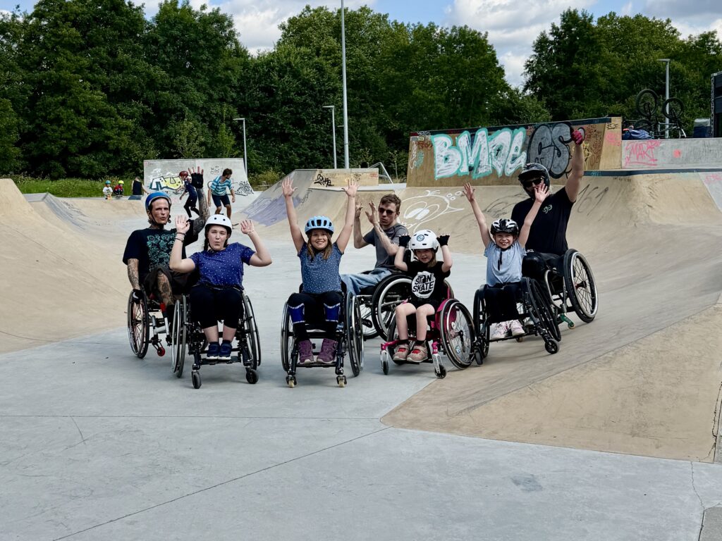 Gruppenfoto von Kindern und Erwachsenen im Rollstuhl im Skatepark.
